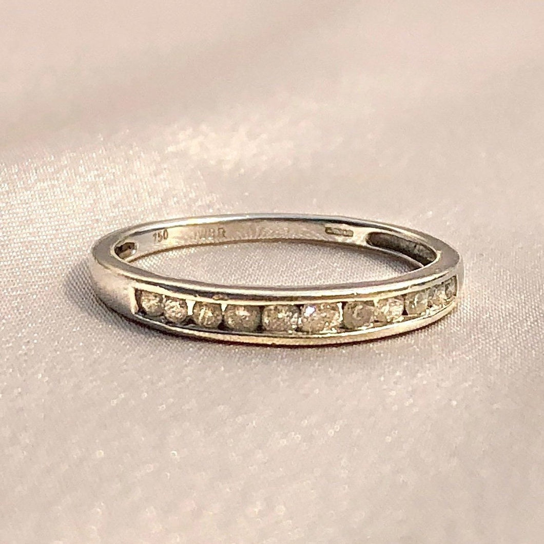 Vintage 18k white gold half eternity band with 11 diamonds in a channel setting. This minimalist ring comes London c 1969. Excellent vintage condition Size: 7.5 Weight: 2.2 grams Band: 2.6 mm (front), 1.7 mm (back) Diamond: 11 diamonds approx. 0.2ctw Hallmarks: crown for gold, 750 for 18k, leopard for London